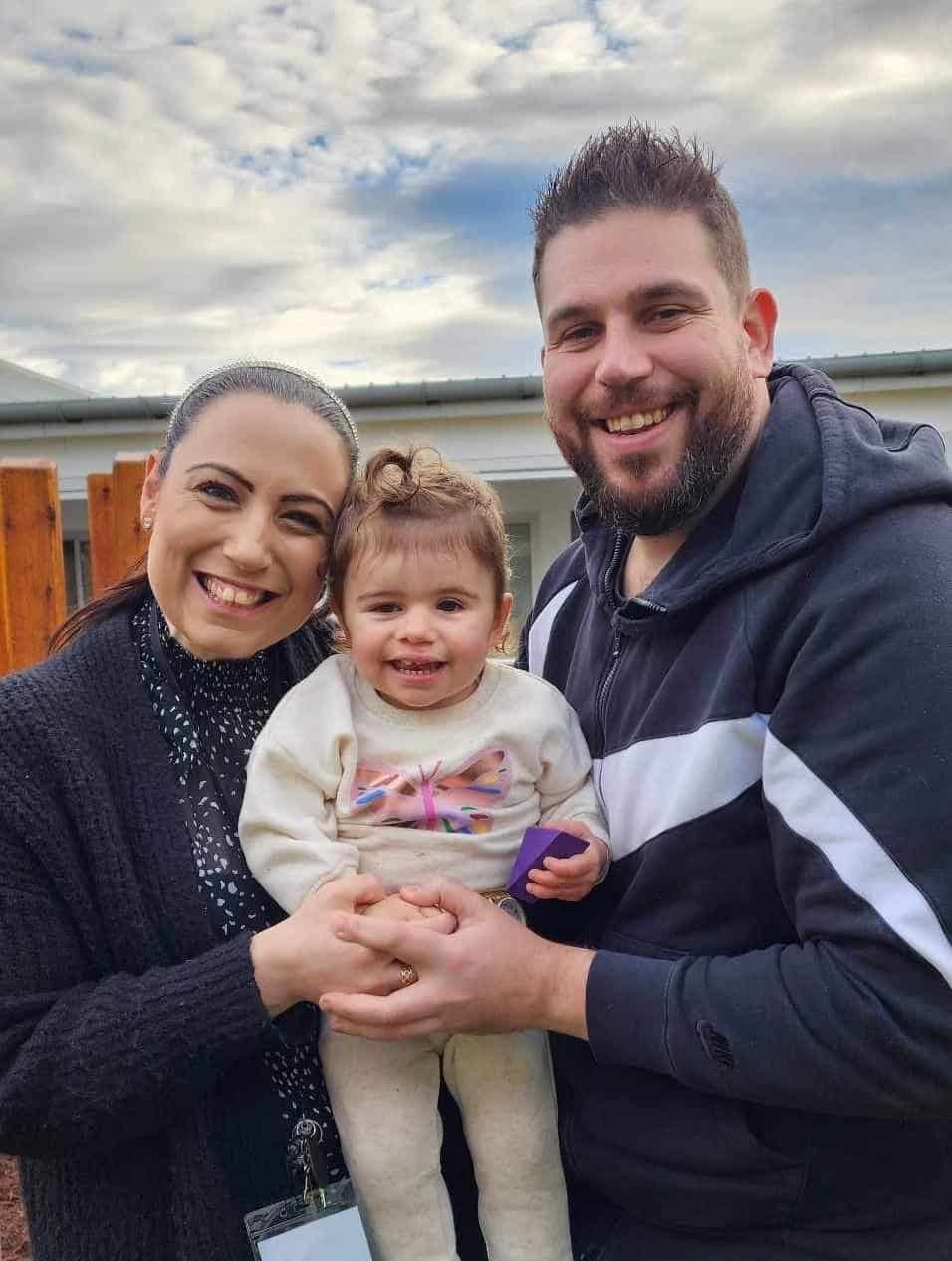 Craniofacial family with young girl, smiling outdoors, promoting craniofacial care and support.