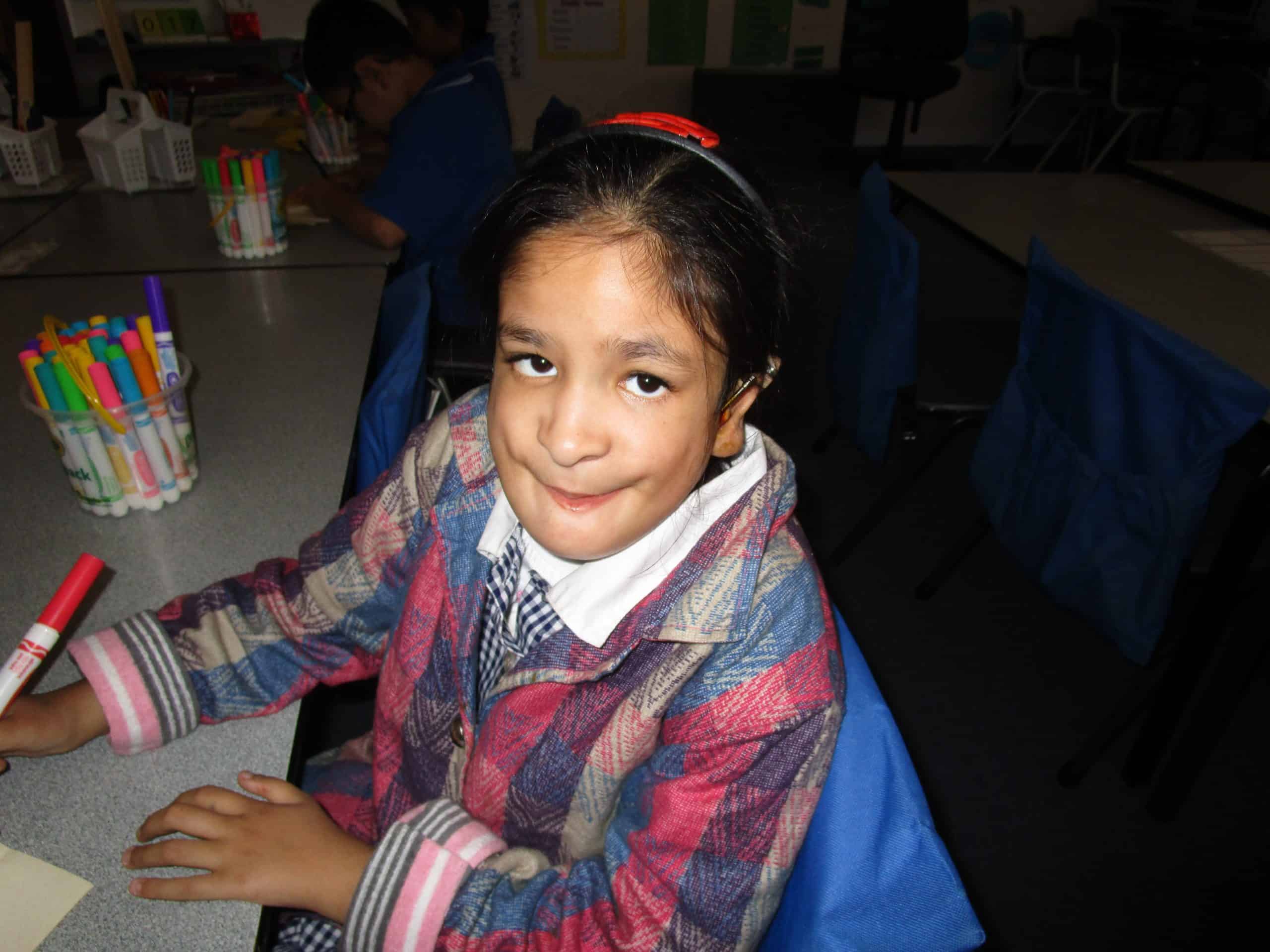 Girl with Nager Syndrome sitting at a desk.