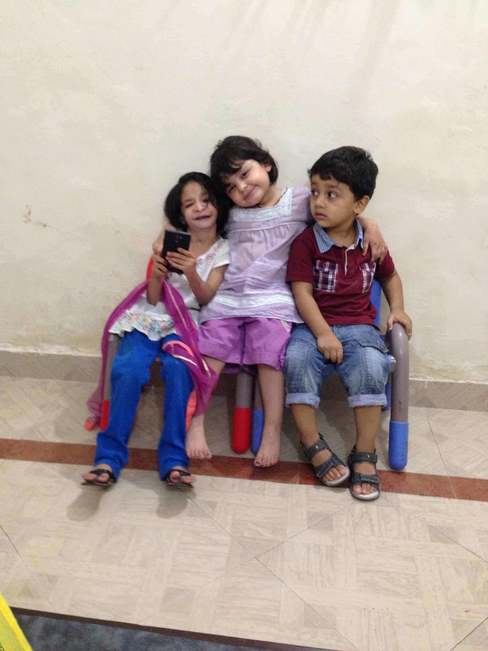 Girl with Nager Syndrome sitting on a bench with her siblings.