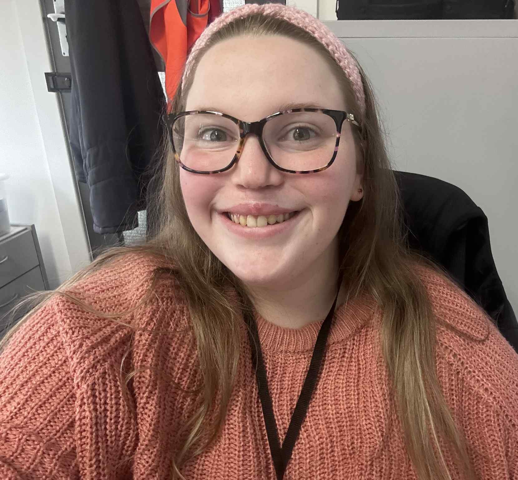Bright smiling young woman who has cleft lip and palate, sitting in an office environment.