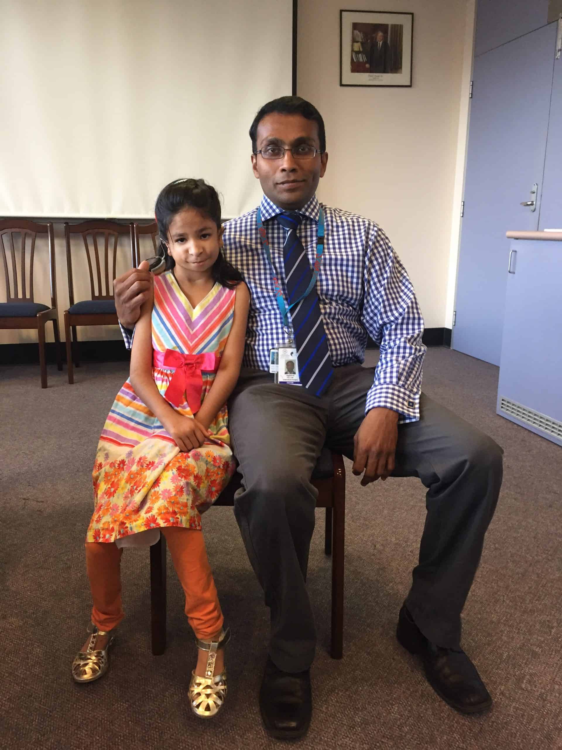 Girl with Nager Syndrome sitting beside a craniofacial surgeon.