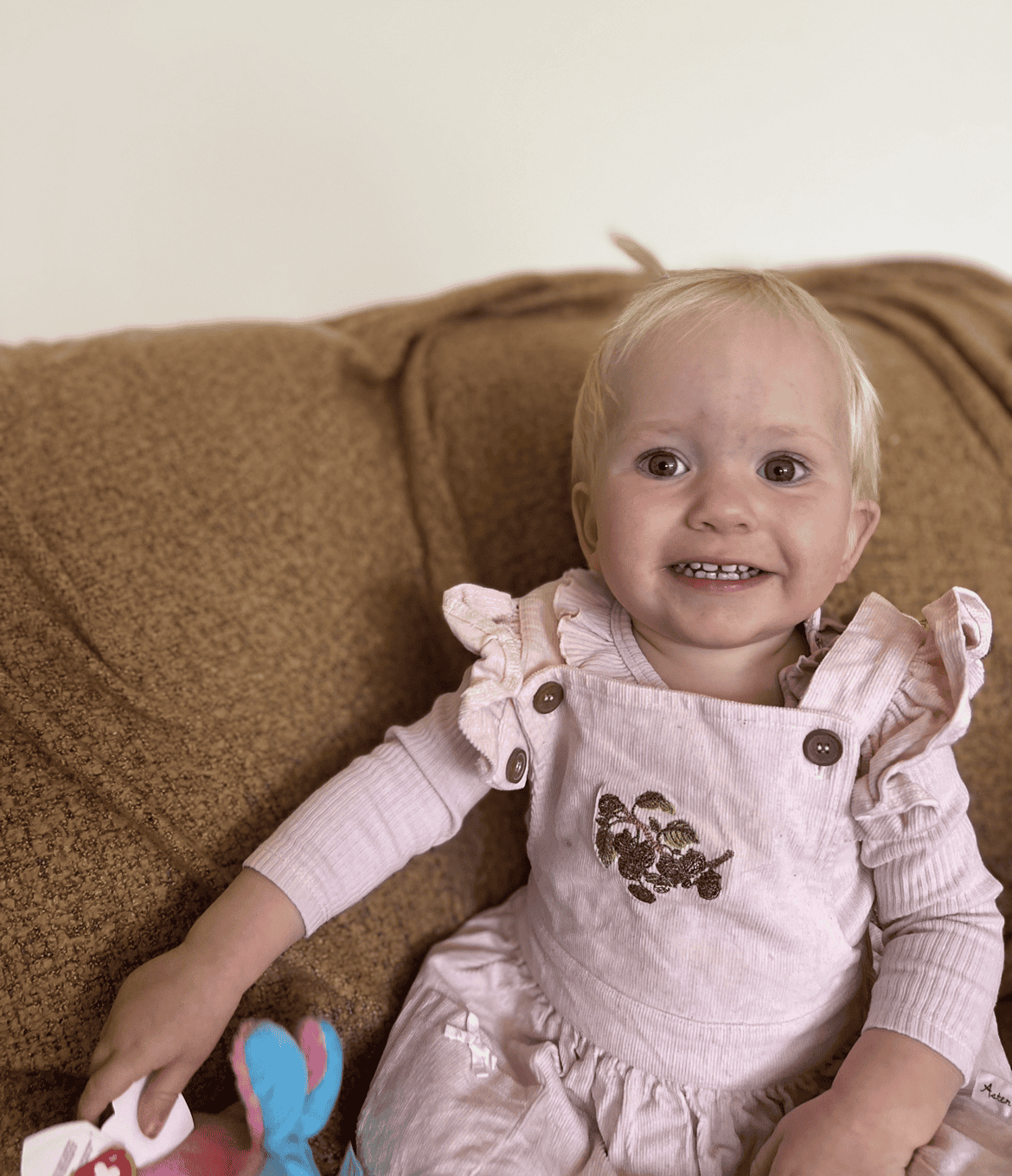 Poppy smiling on a brown couch, highlighting craniofacial care and family support.