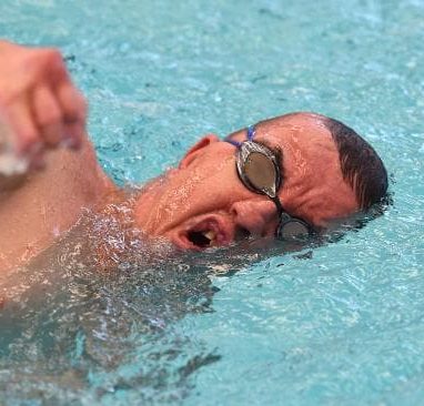 Man with Apert syndrome wearing swim goggles, swimming freestyle