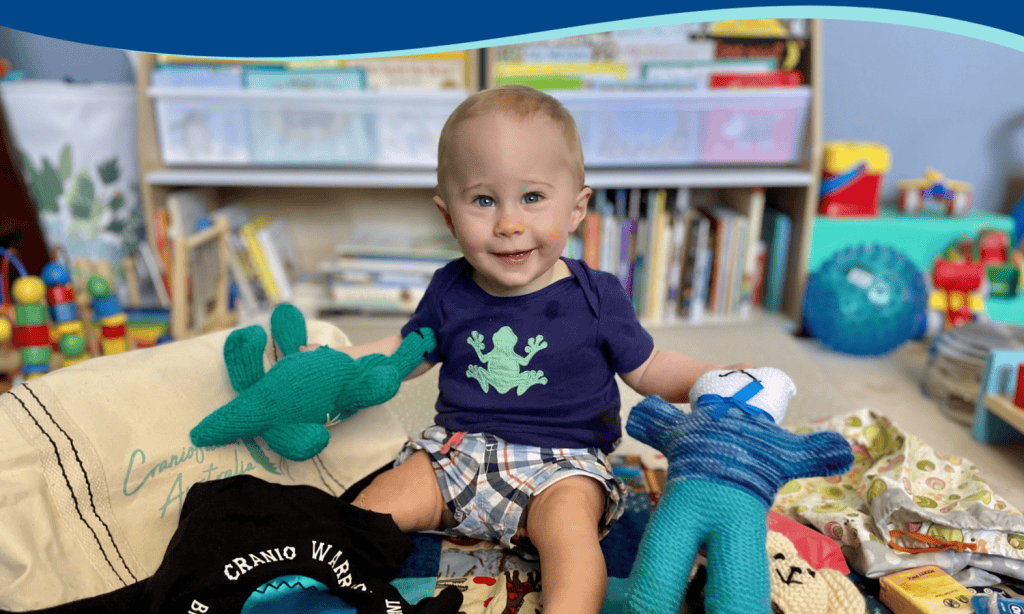 Smiling young boy with toys in a colourful playroom at Craniofacial Australia.
